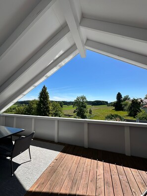 Un balcon avec un plancher en bois, une table et une chaise.