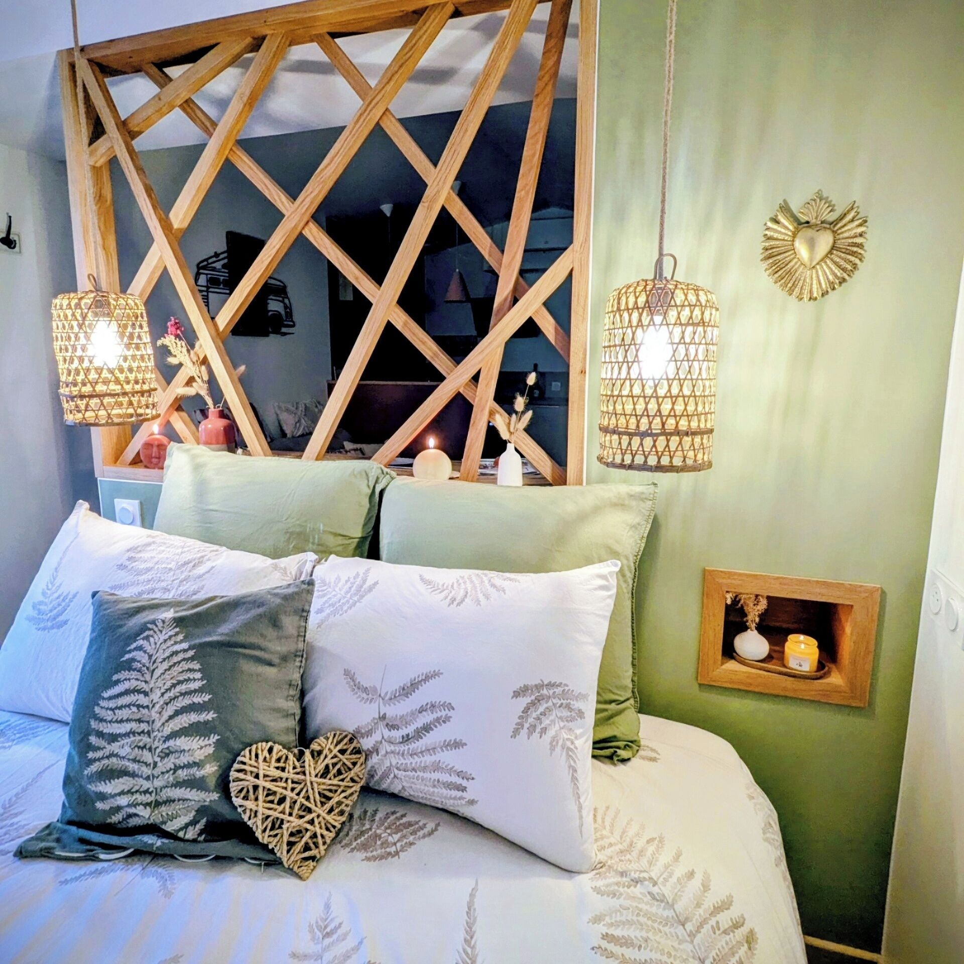 A bedroom with a bed, pillows, a wooden headboard, and two hanging lamps.