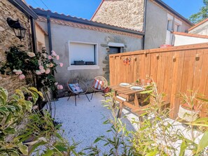 A patio with a wooden table and two chairs, a stone wall, and a wooden fence.