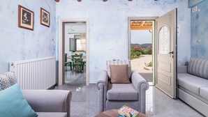 A cozy room with a wooden ceiling, a dining area with a table and chairs, and a view of the outdoors through a door. - Villa Klio (Pitsidia Heraklion Crete)