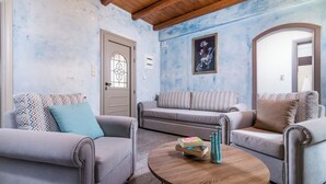 A living room with two sofas, a coffee table, and a door with a glass window. - Villa Klio (Pitsidia Heraklion Crete)