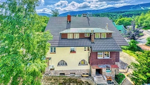 A two-story house with a sloped roof, stone foundation, and multiple windows. - Apartamenty Sun & Snow Strażacka (Karpacz)