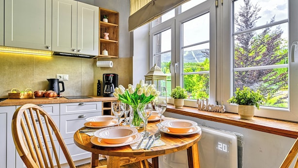 A kitchen with a dining table set for four, a coffee maker, and a view of greenery outside. - Apartamenty Sun & Snow Strażacka (Karpacz)