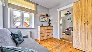 A modern living room with a grey sofa, wooden floor, and a view of the outside. - Apartamenty Sun & Snow Strażacka (Karpacz)