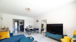 Een moderne woonkamer met een bank, een salontafel, een televisie en een eethoek met stoelen en een tafel.