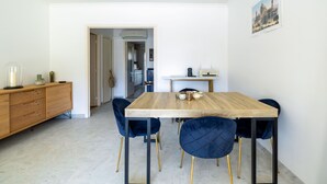 Een eethoek met een houten tafel, donkerblauwe stoelen met bekleding en een houten kast.