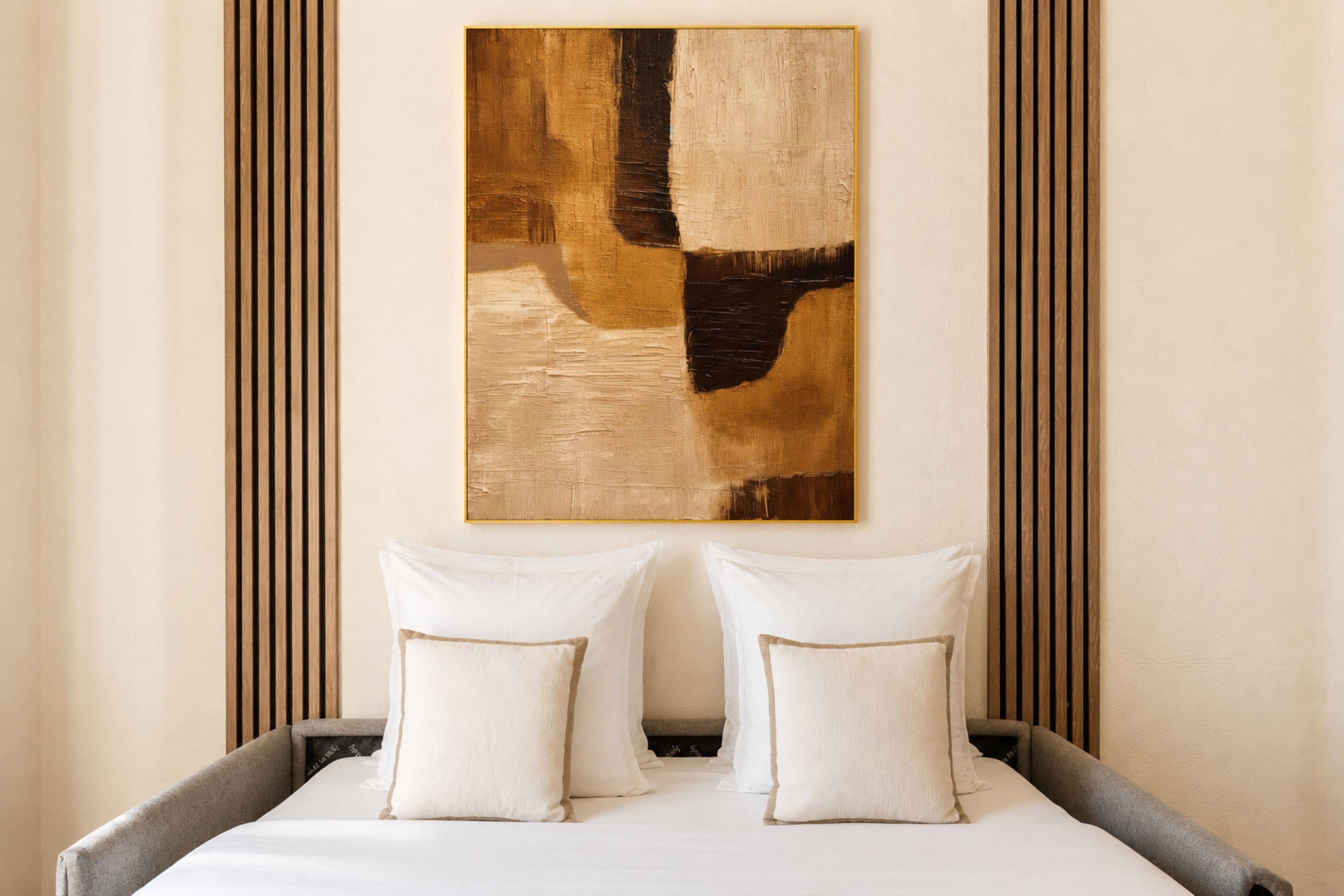 Una cama con dos almohadas y un cuadro abstracto grande sobre ella.