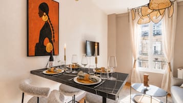 A dining area with a black marble table, white chairs, and a painting on the wall.