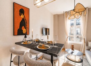 Un comedor con una mesa de mármol negro, sillas blancas y un cuadro en la pared.