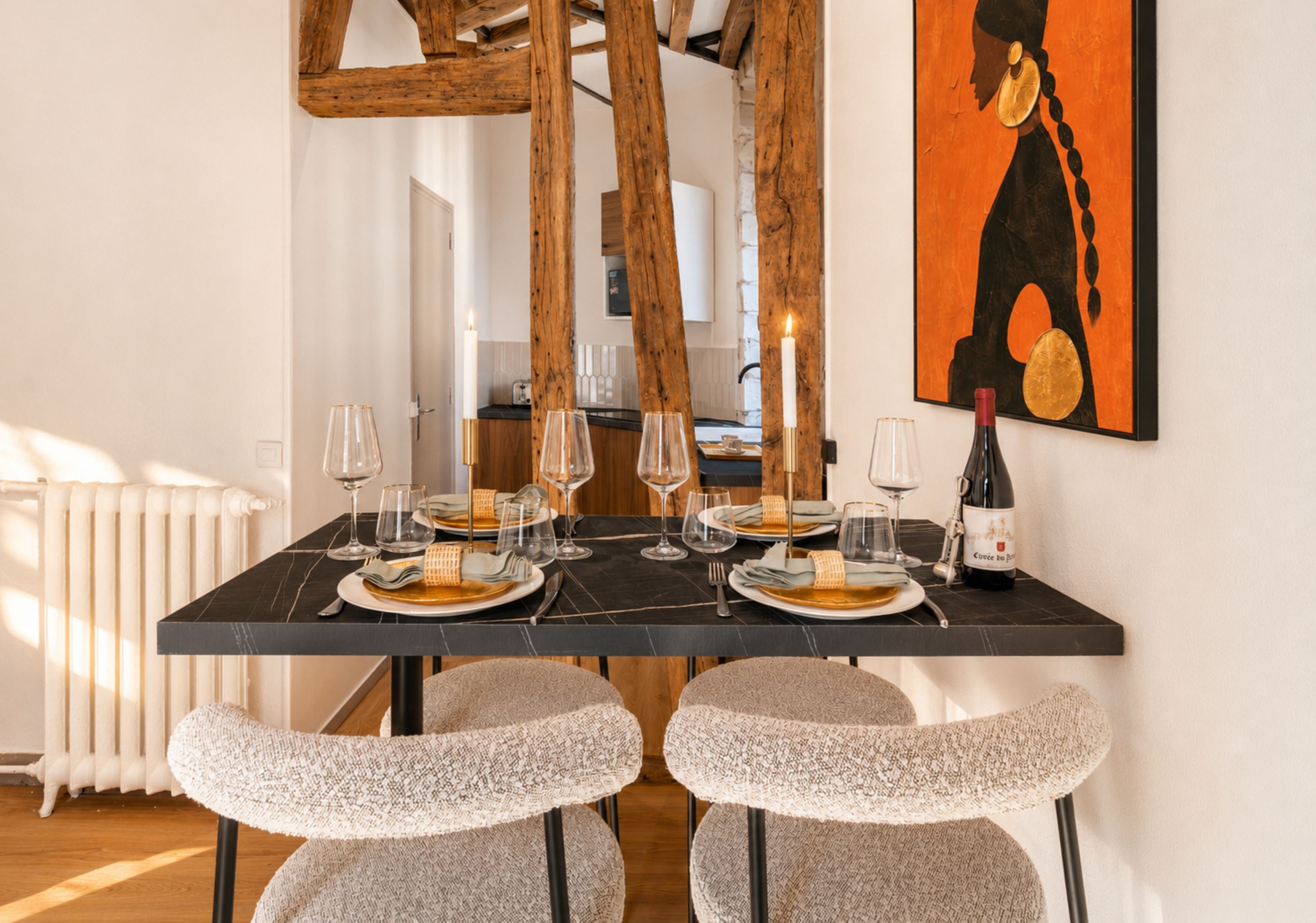 A dining area with a black table set for four, candles, and a wine bottle.