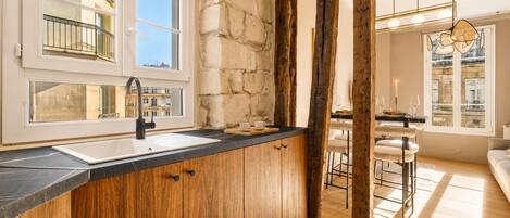 Una cocina moderna con un amplio ventanal, armarios de madera y una zona de bar con taburetes.