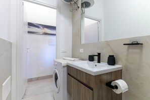 Een moderne badkamer met een wasmachine, een wastafel en een spiegel.