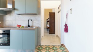 A kitchen with a built-in oven, a microwave, and a sink. There is a door leading to another room.