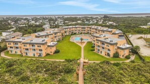 A multi-story residential building with a central courtyard, a swimming pool, and a beach view. - Oceanfront Creston House Condo (Unit 5C) (St. Augustine)
