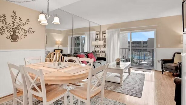 A modern living room with a dining area, large windows, and a balcony. - Oceanfront Creston House Condo (Unit 5C) (St. Augustine)