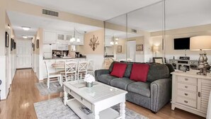 A modern living room with a gray sofa, white coffee table, and a dining area with a white table and chairs. - Oceanfront Creston House Condo (Unit 5C) (St. Augustine)
