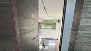 A narrow hallway with wooden walls leading to a kitchen area with white cabinets and a small table with a plant. - Luxury caravan 5 with whirlpool directly on the Achterwasser -holiday homes island Usedom (Lütow)