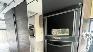Una habitación moderna con puerta corredera, horno empotrado y ventana con vista a árboles.