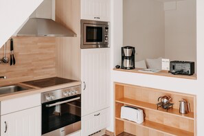 Uma cozinha compacta equipada com micro-ondas Bosch, cafeteira, torradeira e forno.