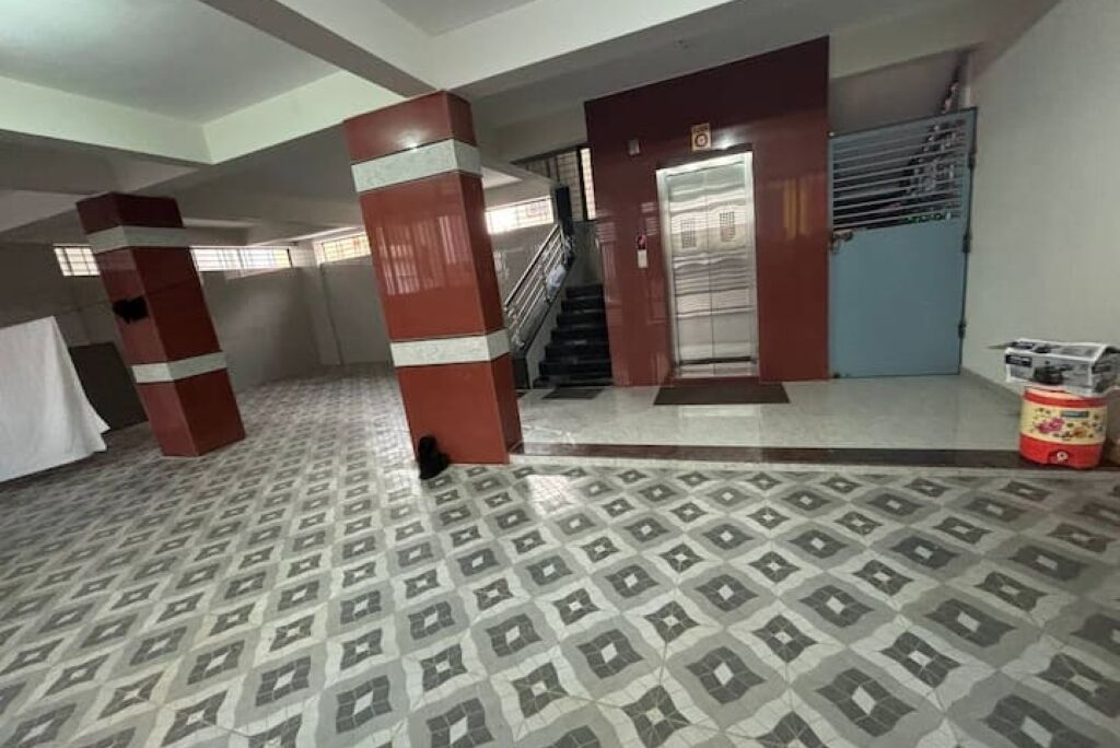 A hotel lobby with patterned flooring, a staircase, and a door leading to an elevator.