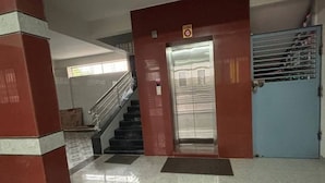 An elevator in a building with a red wall and a blue door. - 1BHK Comfy Stay 4 (Pune)