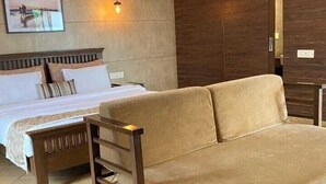 Un dormitorio con cama, sofá, armario de madera y una lámpara de pared.