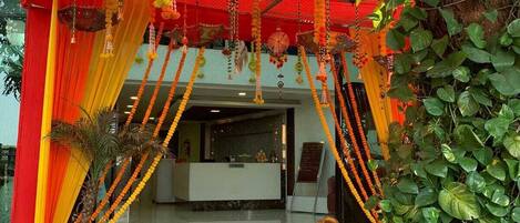 A reception area with a red and yellow draped entrance, a reception desk, and a staircase leading inside.