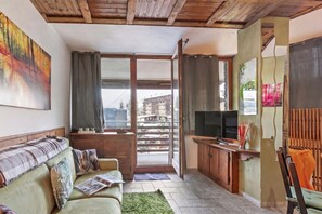 A cozy living room with a sofa, a television, and a view of the outside. - Appartamento My Home With Balcony Town Center (Sauze d'Oulx)