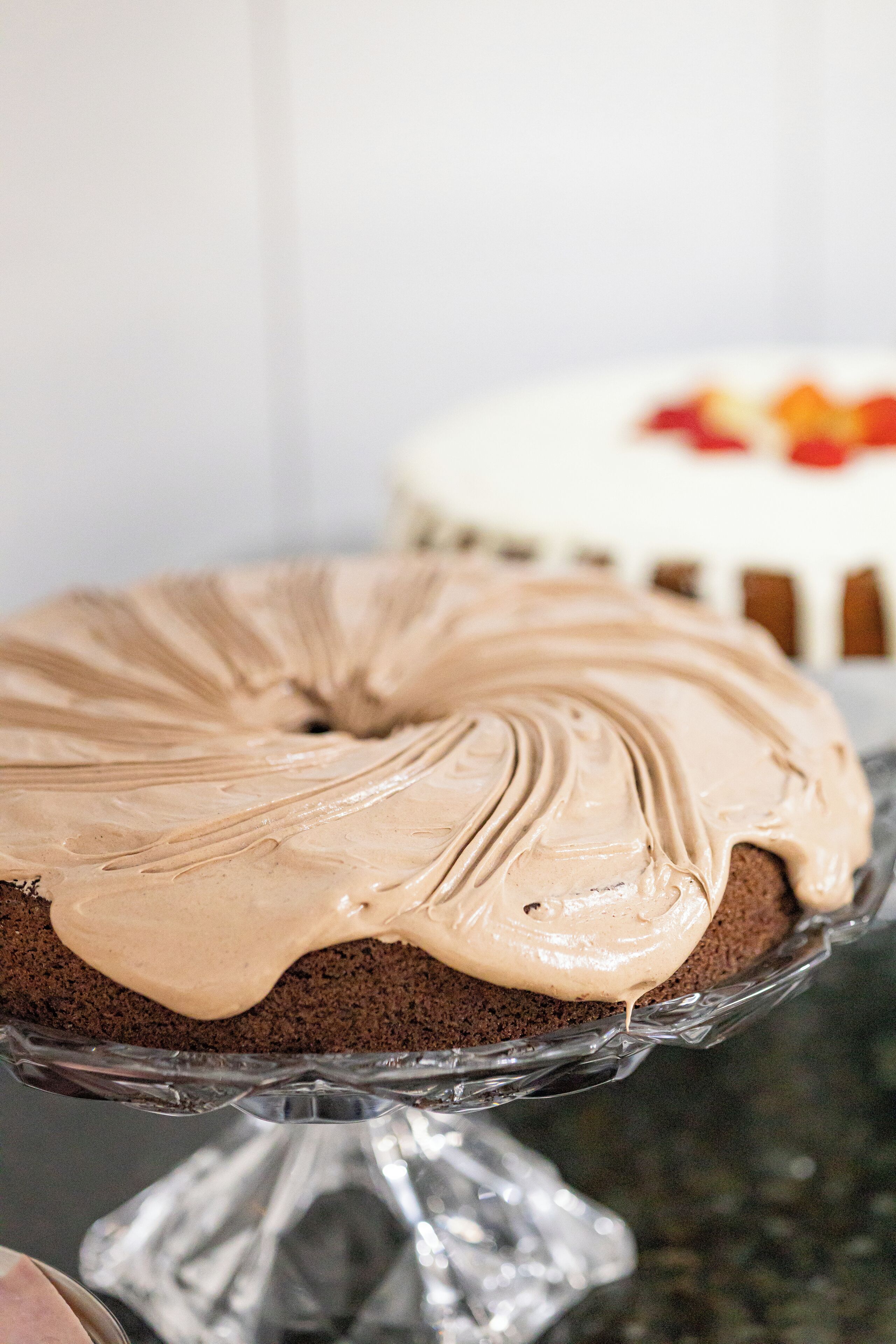 Ein Schokoladenkuchen mit Zuckerguss auf einer Glasplatte.