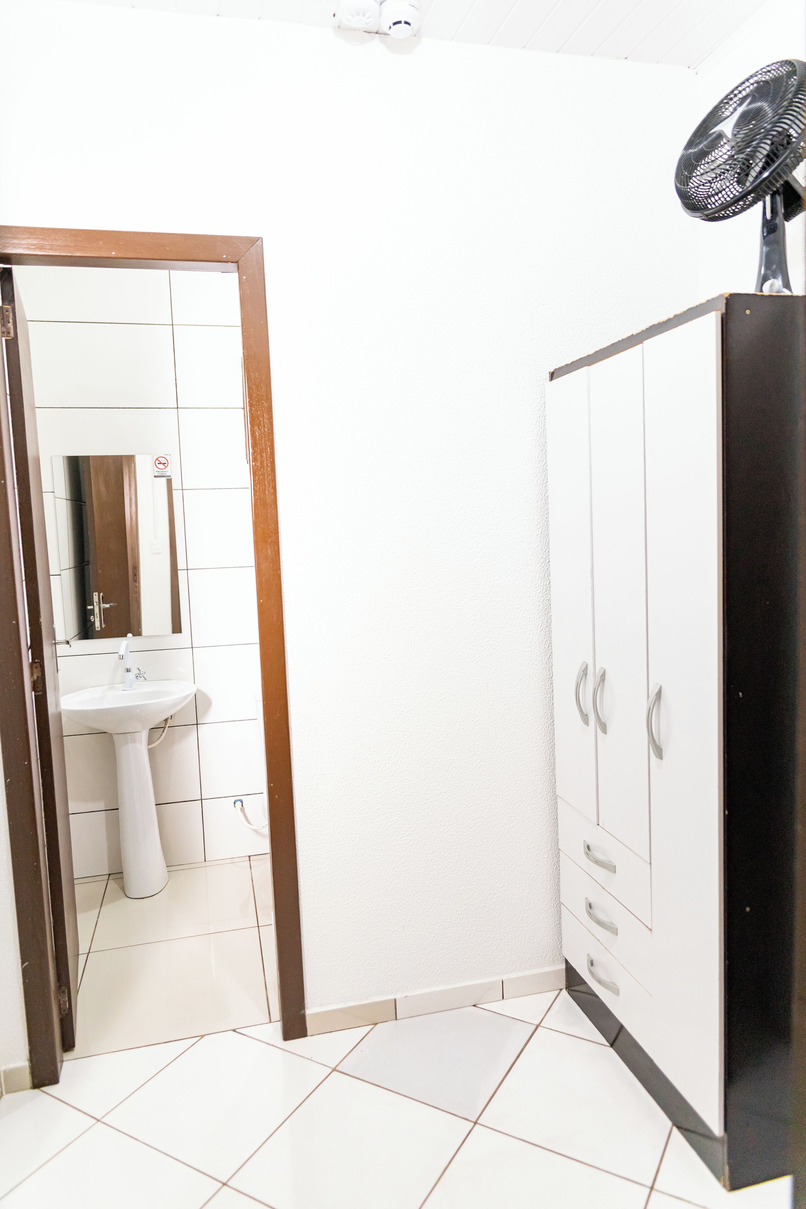A bathroom with a white sink, a mirror, and a black fan.