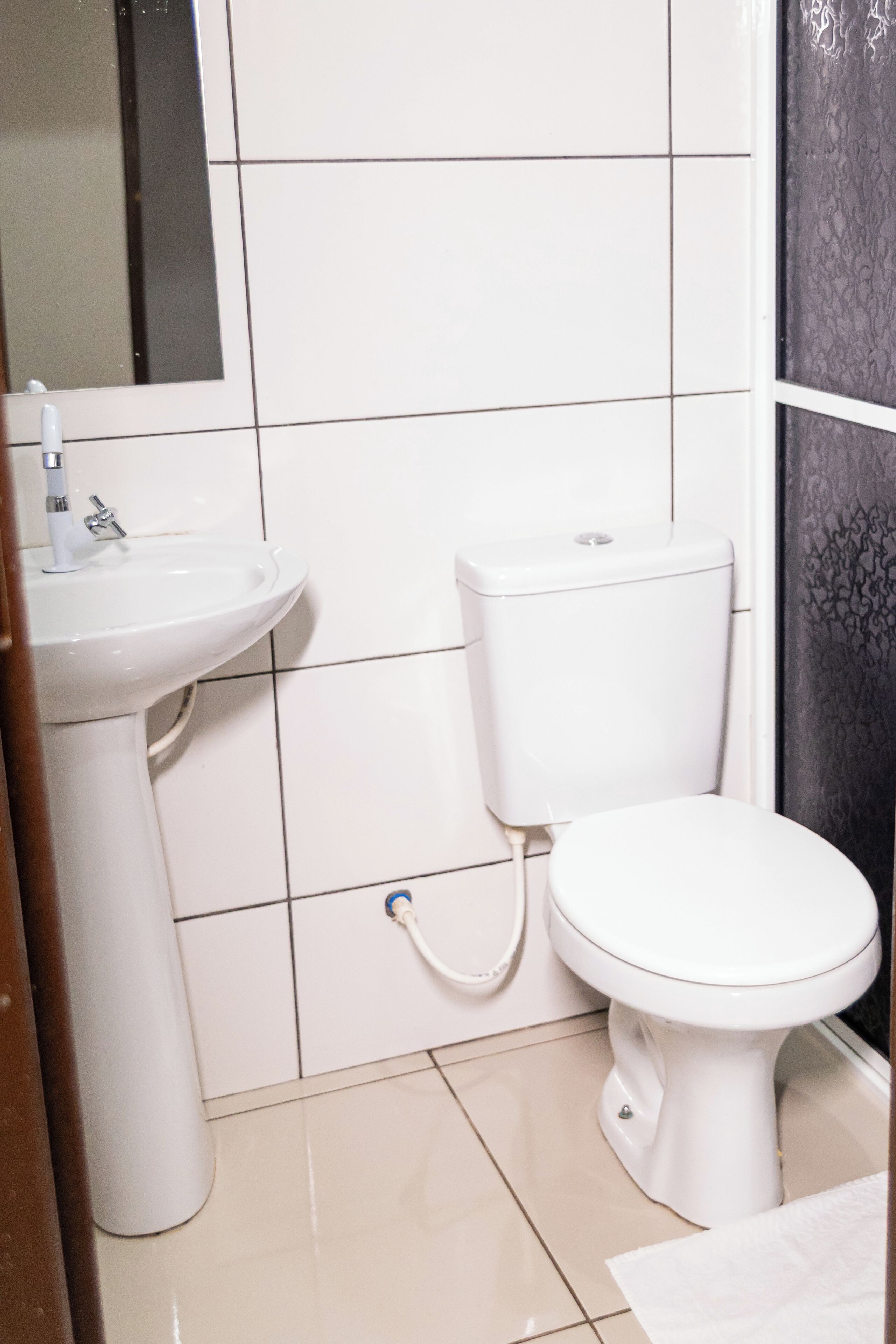 A bathroom with a white sink, toilet, and tiled walls.