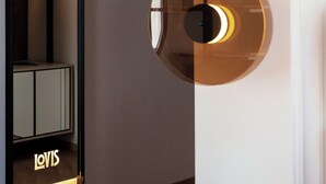 A modern interior with a reflective wall unit displaying the word "LOVIS" and a circular pendant light fixture. - LOVIS Suites Vienna - NEW OPENING (Vienna)