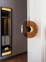 A modern interior with a reflective wall unit displaying the word "LOVIS" and a circular pendant light fixture.