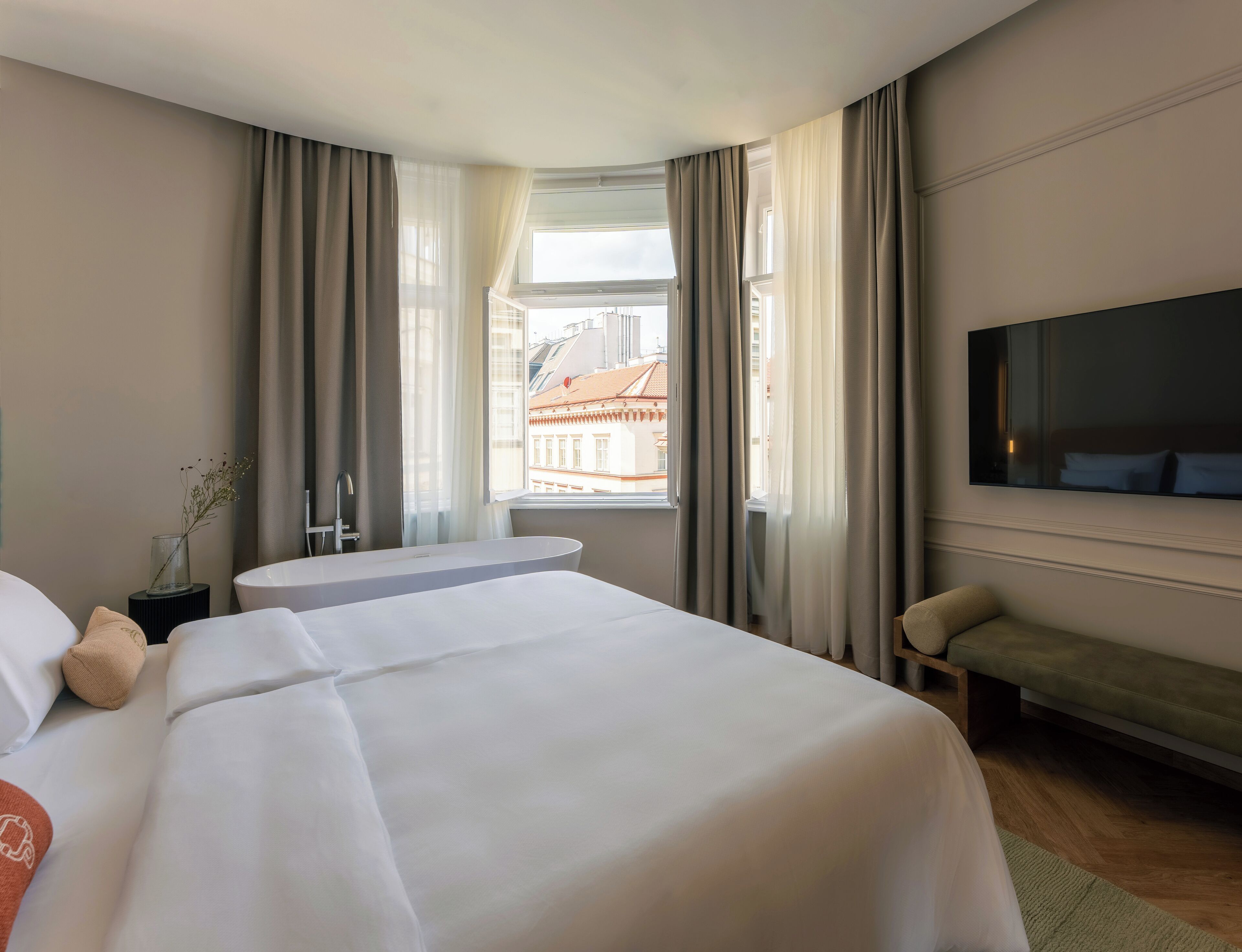 Hotelkamer met twee bedden, een groot raam met gordijnen, een flatscreen televisie en een kleine tafel.