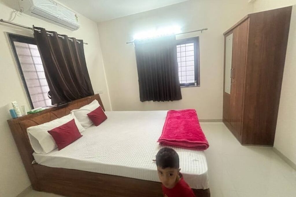 Une chambre à coucher avec un lit en bois, une couverture rouge et une armoire.