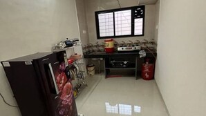 A compact kitchen with a refrigerator, stove, and sink. - 1 bhk comfy stay 2 (Pune)