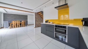Una cocina moderna con una isla central, horno empotrado y salpicadero amarillo.