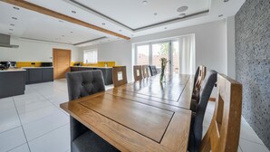 Cocina moderna con comedor, que incluye una mesa de madera, sillas tapizadas de gris y una pared de ladrillo decorativa.