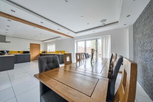 Cocina moderna con comedor, que incluye una mesa de madera, sillas tapizadas de gris y una pared de ladrillo decorativa.