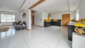 Amplia sala de estar con un sofá, una mesa de centro y una cocina con una pared de acento amarilla.