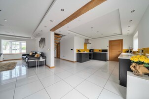 A spacious living area with a sofa, a coffee table, and a kitchen with a yellow accent wall.