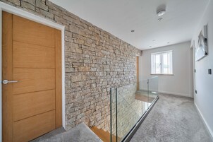 A modern interior with a stone wall, a wooden door, a glass railing, and a window.