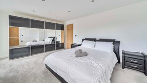 Un dormitorio con una cama grande, un armario con puertas de espejo y una mesita de noche.