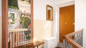 Un corridoio con una panca di legno, un armadietto bianco, uno specchio e una porta.