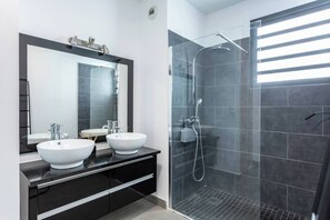 A modern bathroom with two white sinks, a large mirror, and a glass-enclosed shower area. - Les Dunes - Front de Mer de Saint-Paul - Apartment sleeps 6 (Saint-Paul)