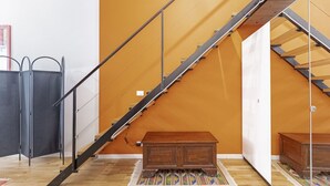 Una escalera con barandales de metal, un banco de madera y un tapete estampado sobre un suelo de madera.