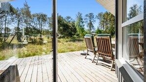 A wooden deck with two chairs and a table, overlooking a forested area. - Stunning home in Strandby with WiFi (Strandby)