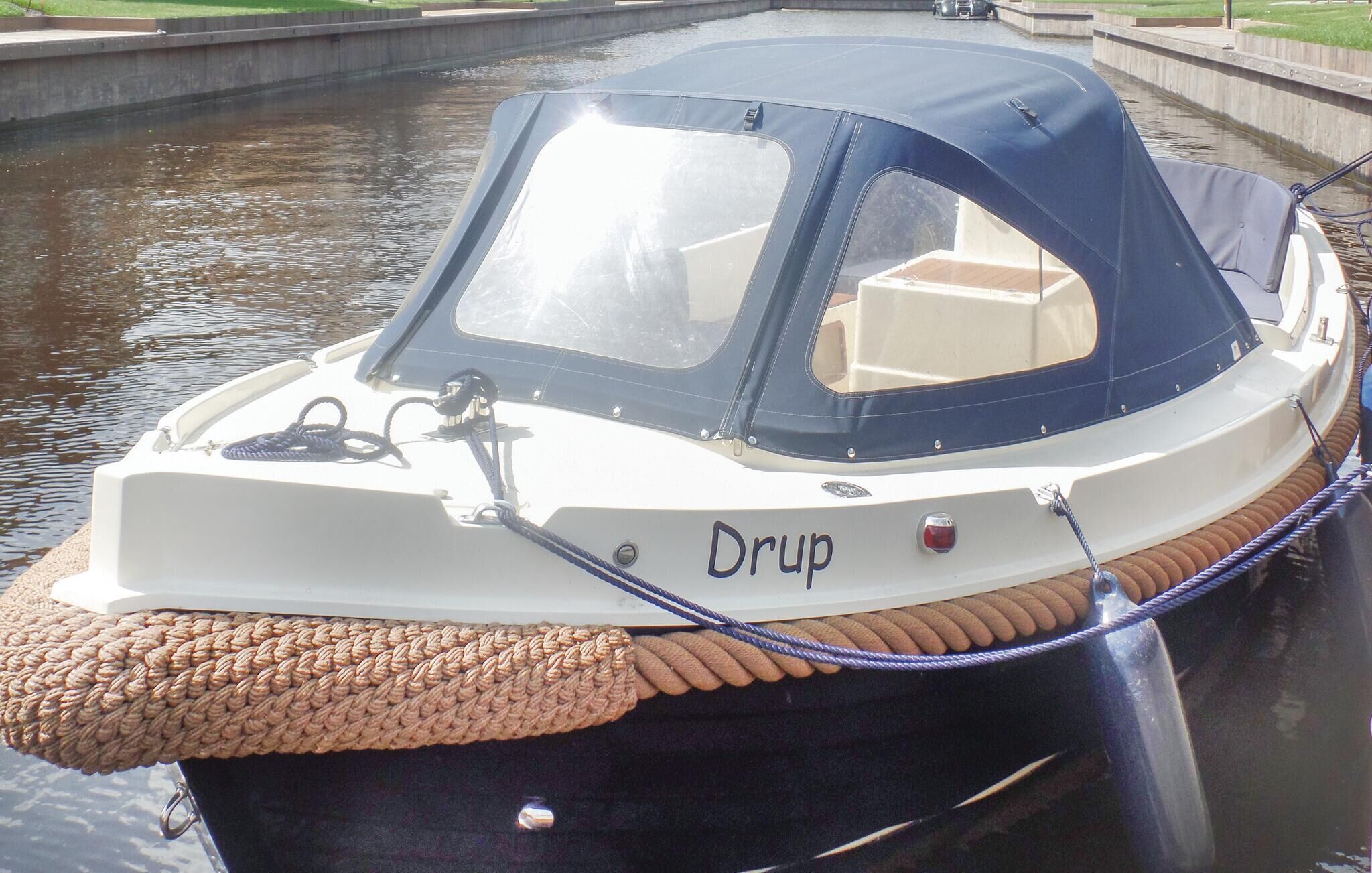 A boat named 'Drup' docked at a canal with a woven cover on the front.