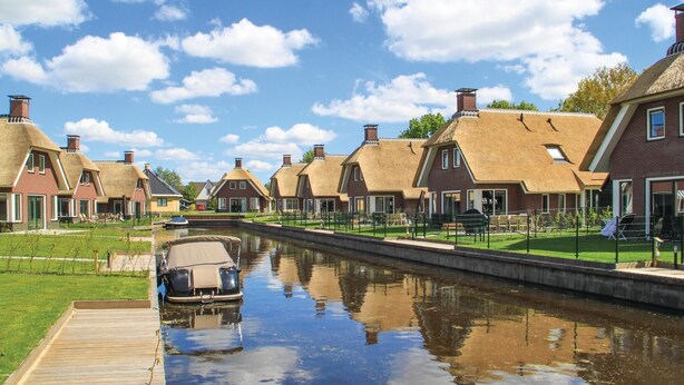 A canal with traditional houses on one side and a modern building on the other. - Stunning home in Idskenhuizen with sauna (Idskenhuizen)