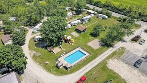 Vista aérea de un camping con vehículos recreativos, una piscina y un camino de tierra.